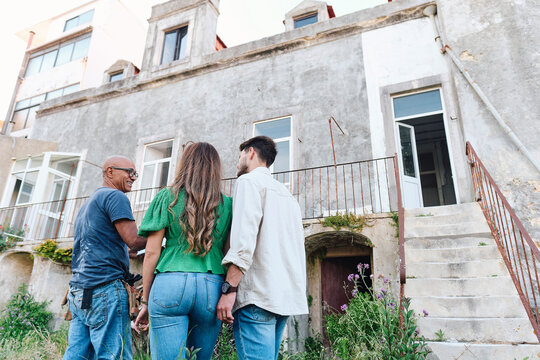 Happy builder having discussion over house with clients at site