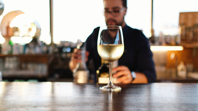 Glass of wine on table with bartender in background
