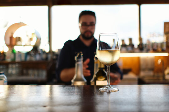 Glass of wine on table with bartender in background at cafe
