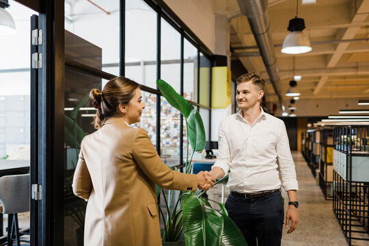 Businesswoman greeting colleague standing at office