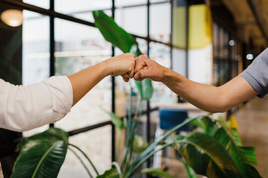 Hands of business colleagues fist bumping at office