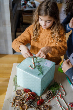 Girl decorating gift box with candy cane at home