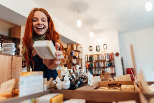 Happy redhead woman holding box and shopping at store