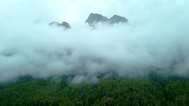 Cinematic establishing shot of mountain top surrounded by mist and heavy fog