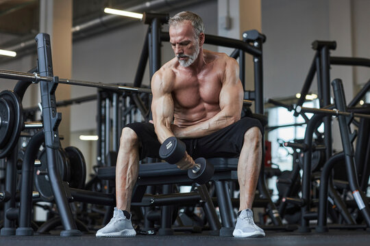Handsome man exercising with dumbbell in health club