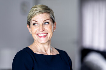 Happy mature woman with short blond hair at home