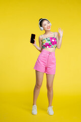 Happy smiling young asian woman relaxed with smartphone, listening music in wireless headphones