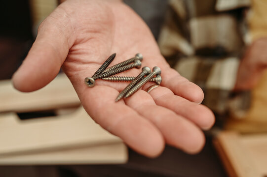 Hand of man holding metal screws