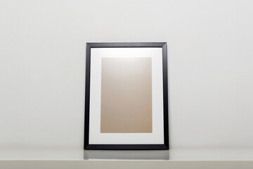 black picture frame on a table. Stylish photoframe with passe-partout
