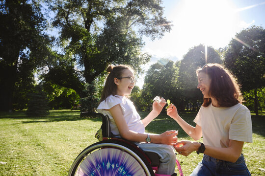 Happy daughter in wheelchair with mother enjoying at park