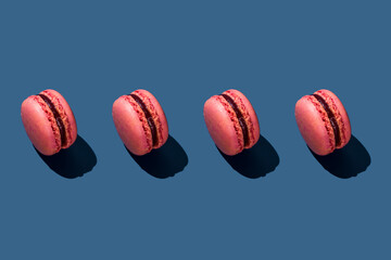 Pink macaroons arranged on blue background
