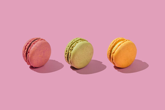 Colorful macaroons in a row on pink background