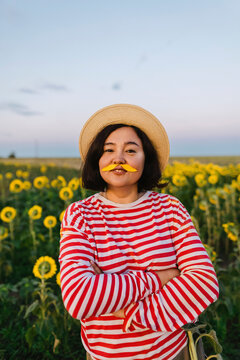Mature woman with sunflower petals mustache in field