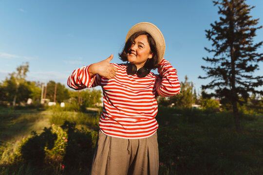Smiling woman with hat gesturing thumbs up in field
