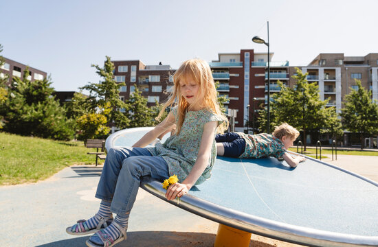 Brother and sister playing on playground on sunny day