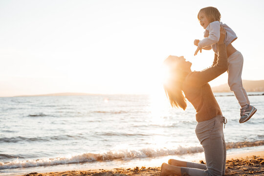 Happy mother lifting daughter up in air at beach