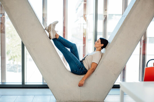 Businesswoman resting on V-shaped column in office corridor