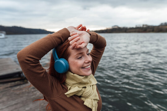 Smiling woman listening to music by lake
