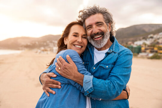 Happy senior couple embracing at beach on weekend