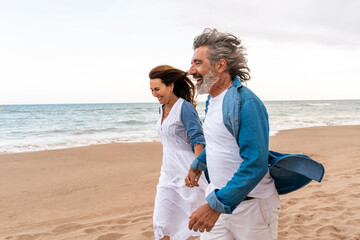 Happy senior couple enjoy walking on sand by sea