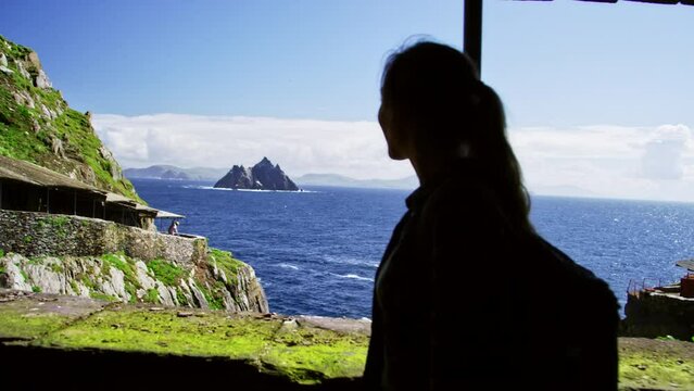 Silhouette of a young woman walking by ocean cliffside