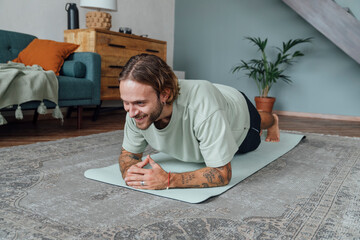 Happy young man practicing yoga at home
