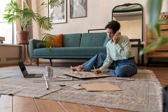 Activist making environment placard and talking on smart phone in living room at home