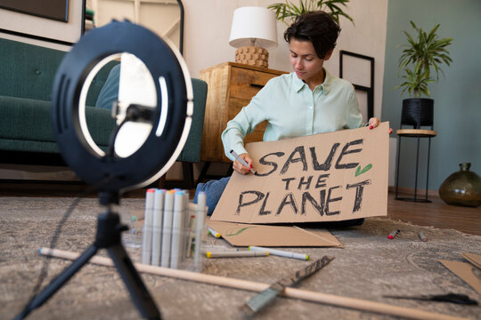 Activist with environment placard vlogging at home
