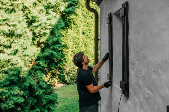 Man installing window of house in backyard
