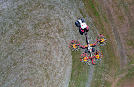 Drone view of tractor with rotary rakes turning hay