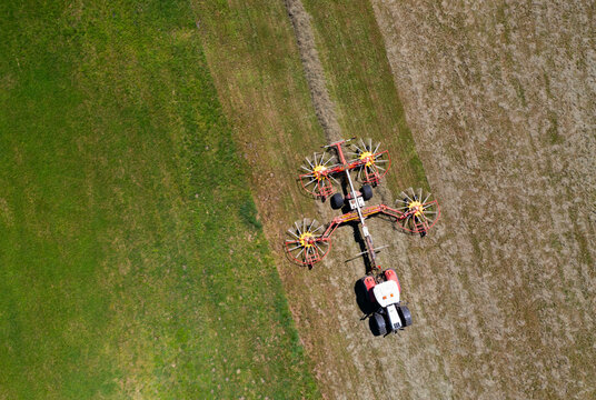 Drone view of tractor with rotary rakes turning hay