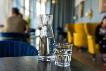 Glass of water and carafe on wooden table in cafe, atmosphere of a coffee shop in bokeh background - 644374606