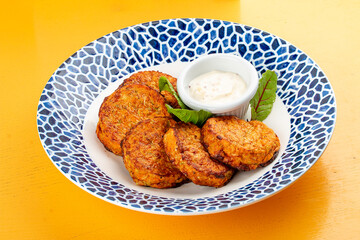 Pumpkin cutlets with white sauce in a decorative plate. Vegetarian dish. Isolated image on a white background.