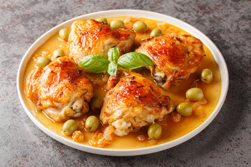 Mediterranean chicken thigh baked with green olives and onion paprika sauce close-up in a plate on...
