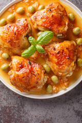 Spanish chicken baked with olives and onions close-up in a plate on the table. Vertical top view from above