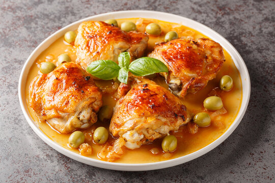 Mediterranean chicken thigh baked with green olives and onion paprika sauce close-up in a plate on the table. Horizontal