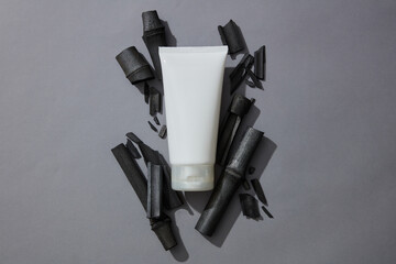 Empty label tube in white color placed on a pile of activated charcoal sticks. Activated bamboo...