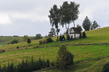 Hillside chapel in meadow during morning fog