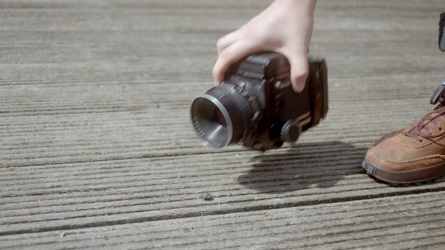 Person Picks Up Mamiya RB67 Digital Camera From The Ground. closeup