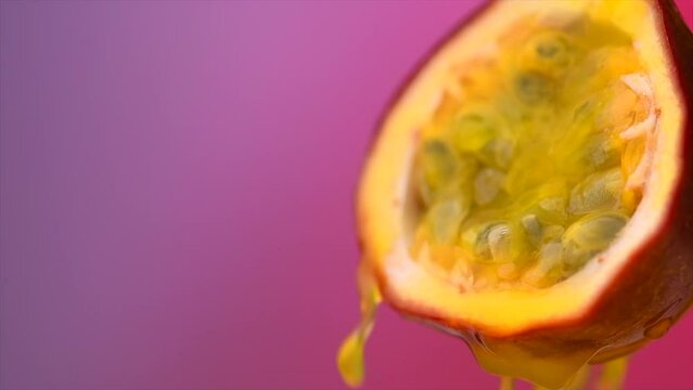Passion fruit juice splashing, flowing. Maracuya exotic fruits juicy splash. Violet, purple background. Ripe and fresh healthy vegan food and drinks, slow motion