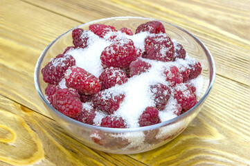 fresh raspberries with sugar on wooden background