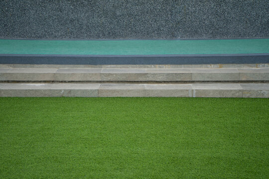Long concrete seat with lawn grass and rock wall background.  Step or layer of the sport indoor and outdoor.