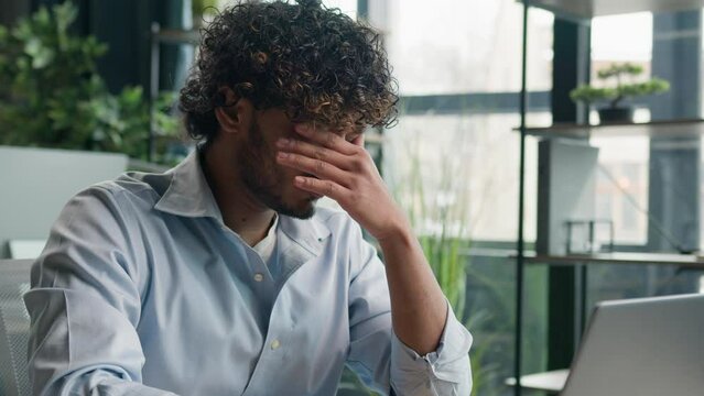 Tired man Arabian exhausted Indian latino male business person office worker sick businessman rubbing dry itchy eyes feel eye strain fatigue feel headache bad vision overwork with laptop computer work