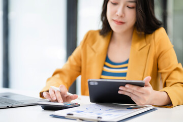 Business woman working on laptop and accounting financial report, accountant using calculator to calculate tax refund at office.