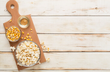 Prepared popcorn with ingredients on wooden background, top view