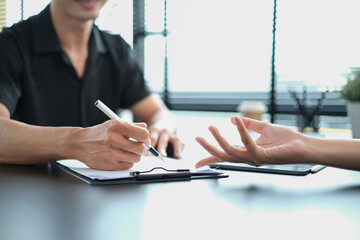 Cropped shot of human resources manager helping new employee to fill and sign employment agreement