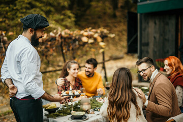 An idyllic scene of people enjoying a garden lunch, surrounded by lush greenery and vibrant flowers.