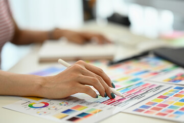 Creative woman using digital tablet and working with choosing color samples on desk at graphic studio