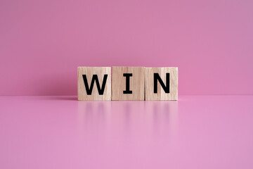 Wooden blocks form the text "WIN" against a pink background.