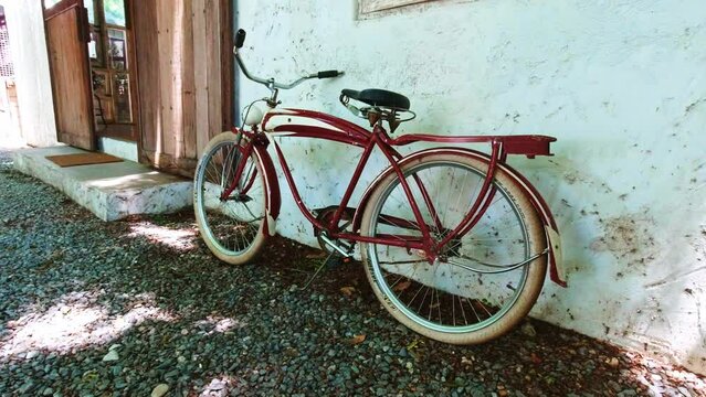 Classic Red Bicycle Resting Against a White Wall Next to a Sliding Door Entrance to a Cafe in Bangkok, Thailand.